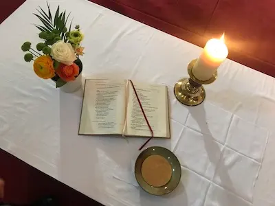 Livre de prière ouvert sur l’autel, entre un bouquet, un cierge et une patène